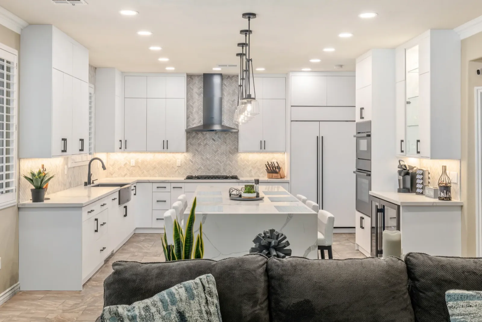 The finished kitchen with the waterfall island, herringbone backsplash and pendant lights